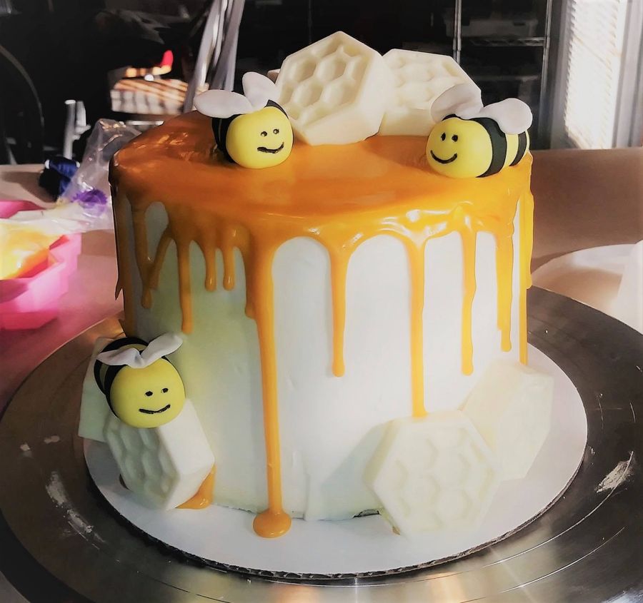 White cake with honey drip, smiling bumblebees and chocolate honeycomb