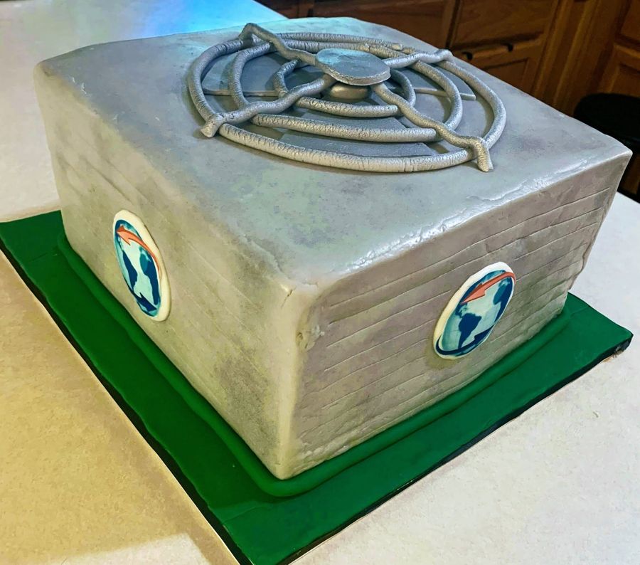 Silver sculpted cake with a company globe logo on each side