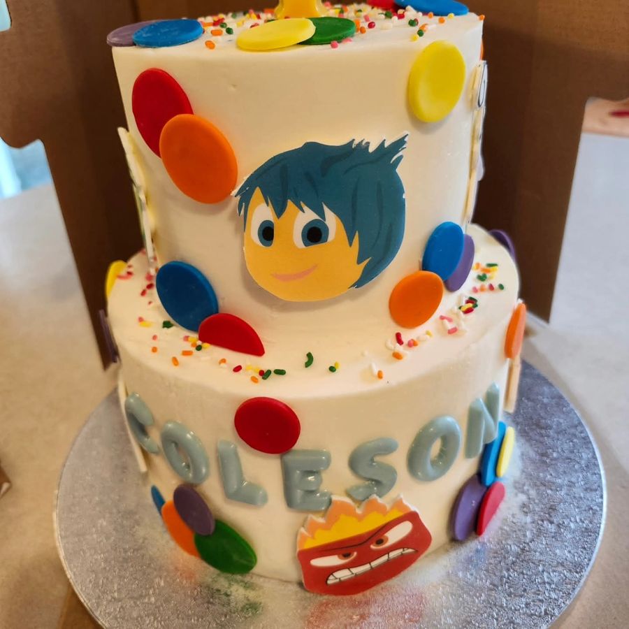 Two-tier Inside Out cake with emotion characters and colorful dots