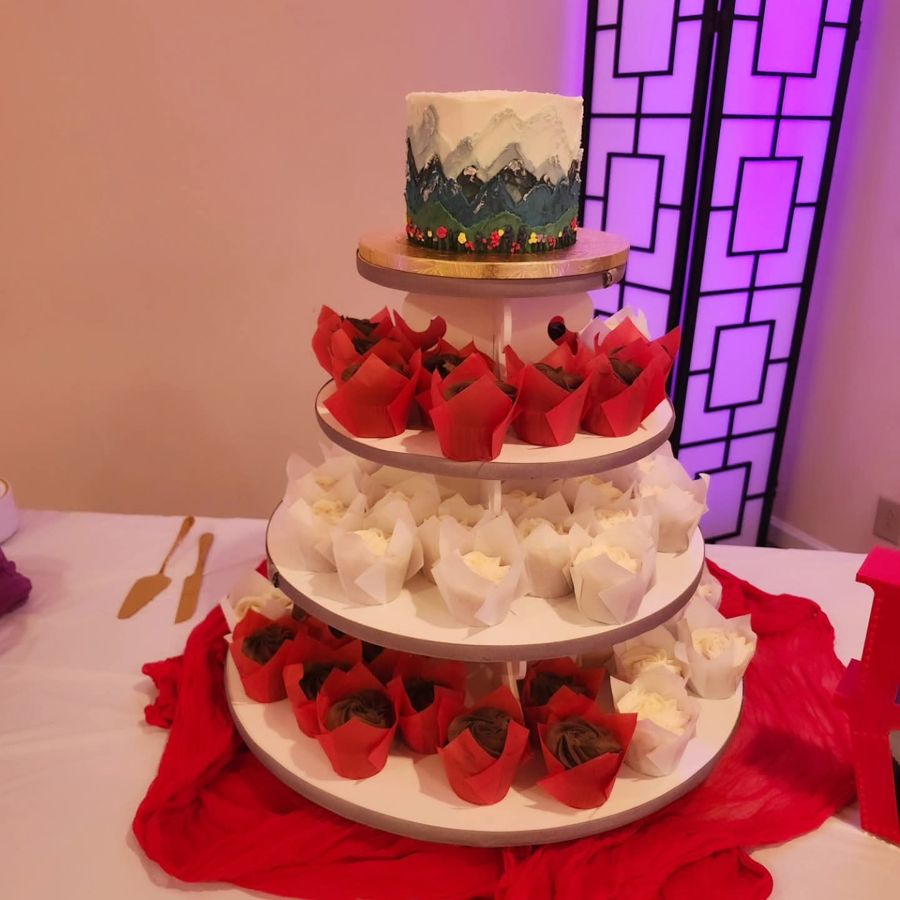 Painted mountain cake on top of a four-tier cupcake tower