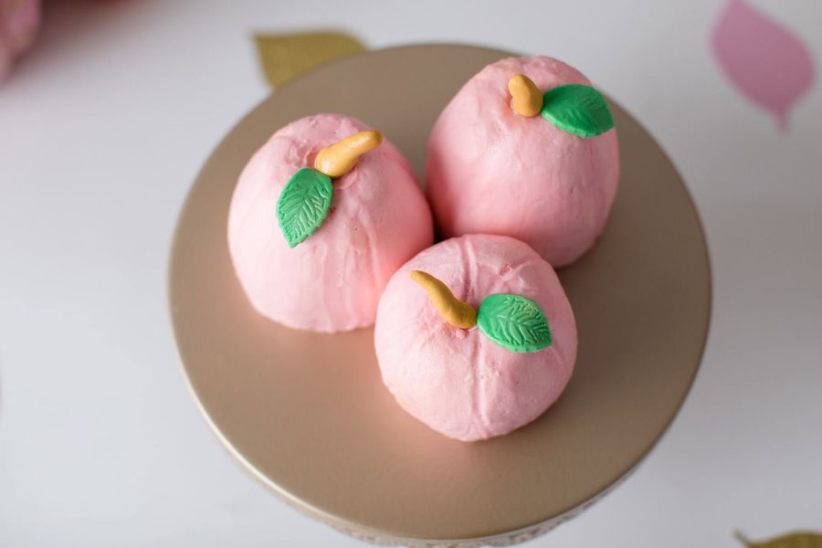 Pink candy-coated cake bites shaped like apples with leaves