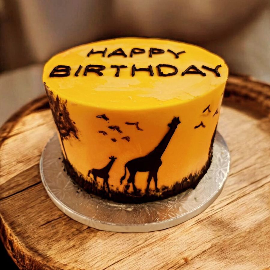 Golden sunset safari cake with painted giraffe and tree silhouettes
